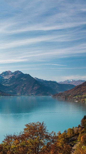 Image green and brown mountain beside lake under blue sky during daytime