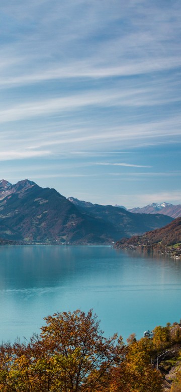 Image green and brown mountain beside lake under blue sky during daytime